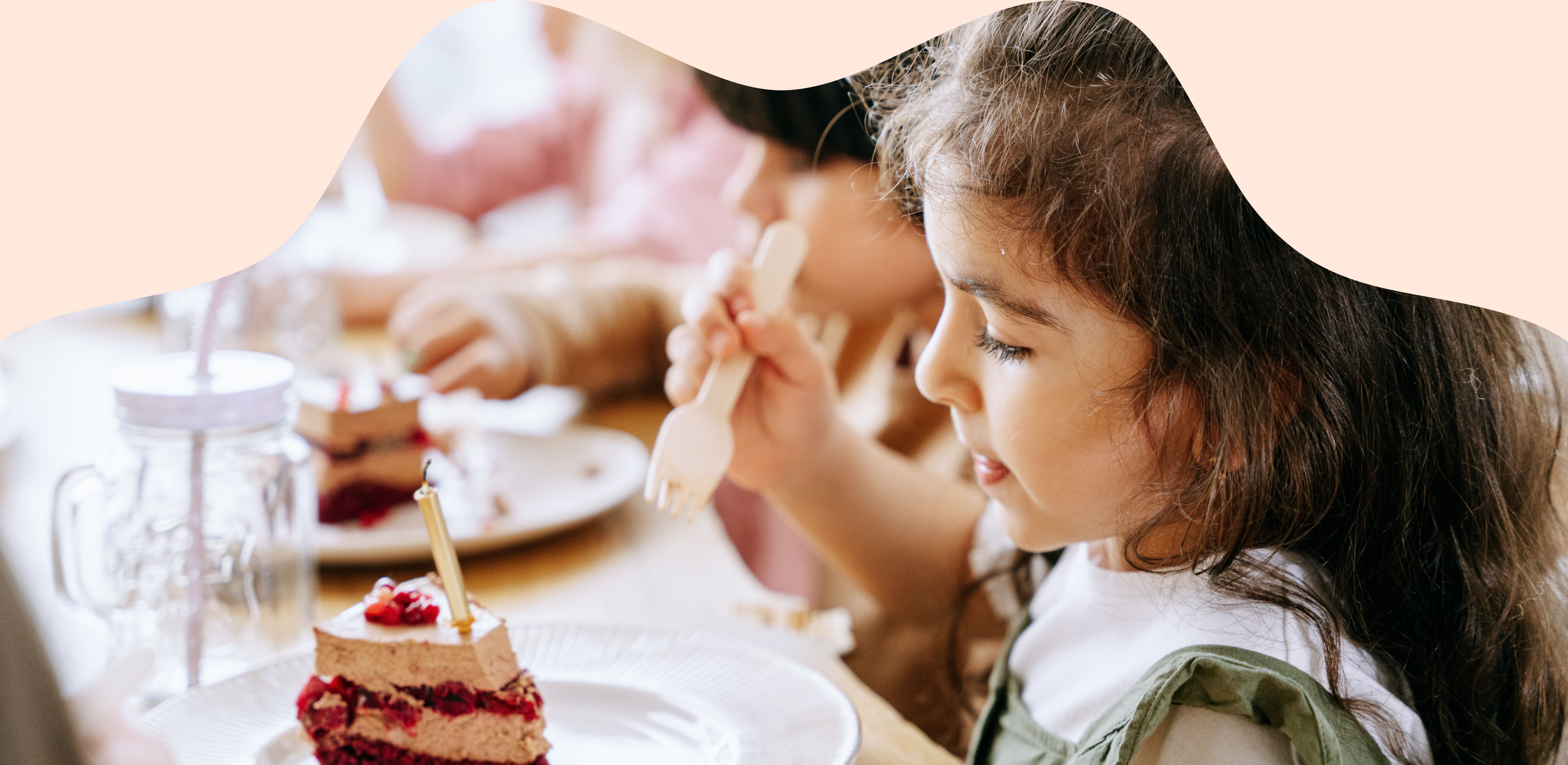A young girl enjoying a slice of cake at a party table