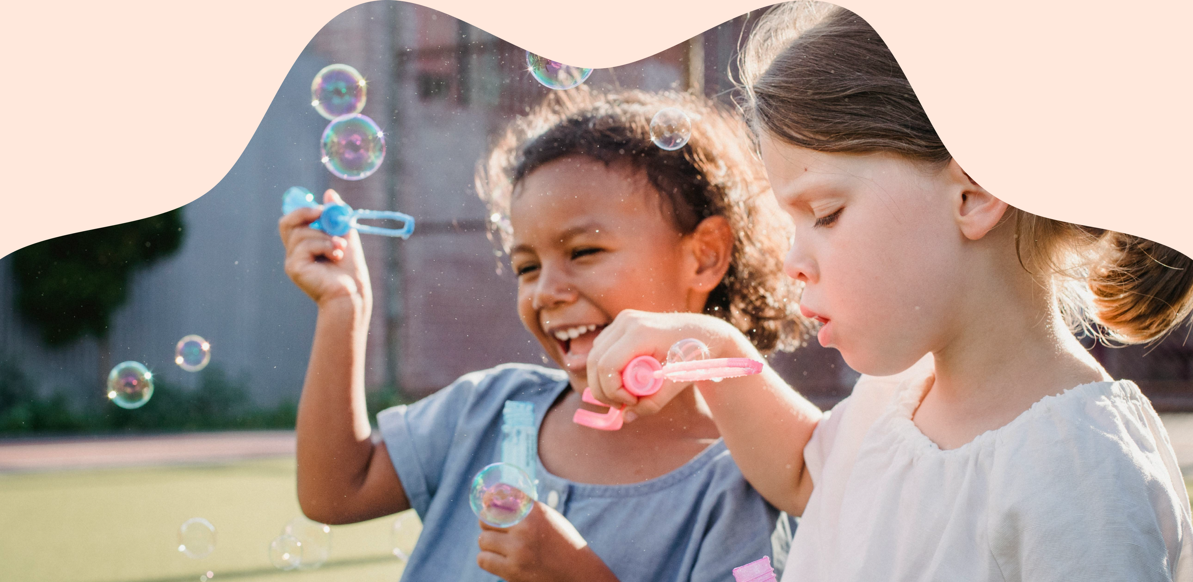 Two children blowing bubbles together outdoors