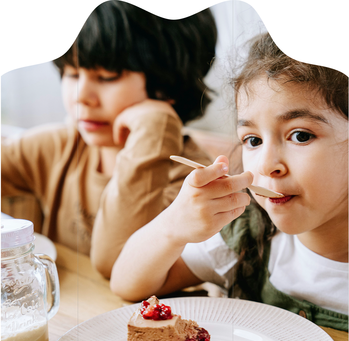 Two children eating cake together at a table